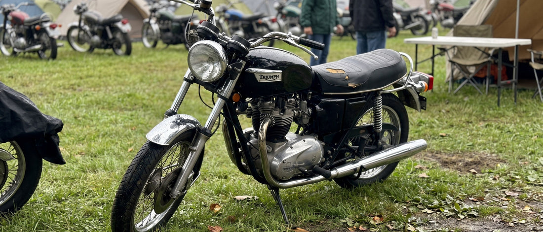Custom motorcycle seat covers finish a vintage Triumph rebuild parked at an outdoor show field