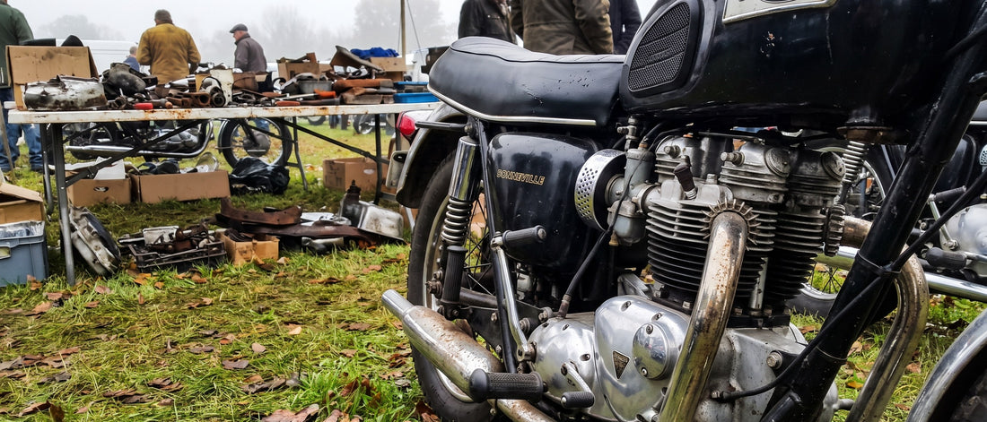 Lambskin motorcycle seat cover topic shown on vintage Triumph Bonneville parked at a shaded swap meet