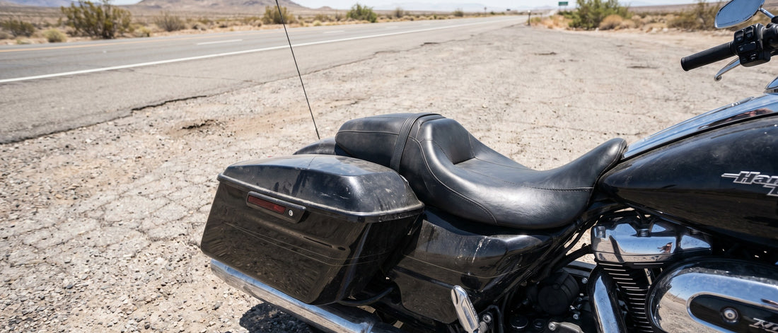 Harley Road Glide bagger parked at desert roadside pull-off, factory black vinyl seat baking in midday sun, long-ride fatigue