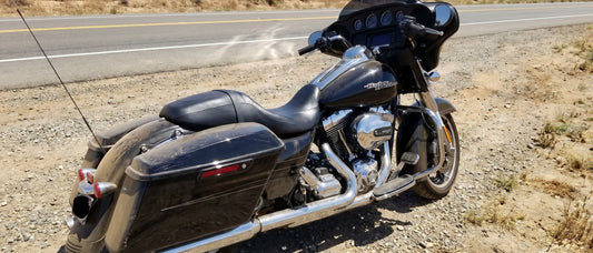 Sheepskin motorcycle seat cover question shown on Harley Street Glide parked on shimmering summer highway
