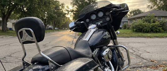 Harley Street Glide with rider backrest parked on a tree-lined street at early morning before a long ride