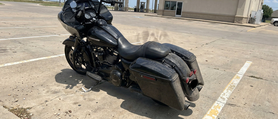 Harley Road Glide motorcycle parked on a hot concrete parking lot at midday with heat shimmer rising off the black vinyl seat