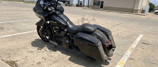Harley Road Glide motorcycle parked on a hot concrete parking lot at midday with heat shimmer rising off the black vinyl seat